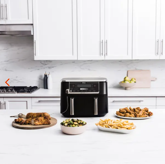 
Gedeckter Tisch mit frittierten Speisen und Airfryer im Hintergrund